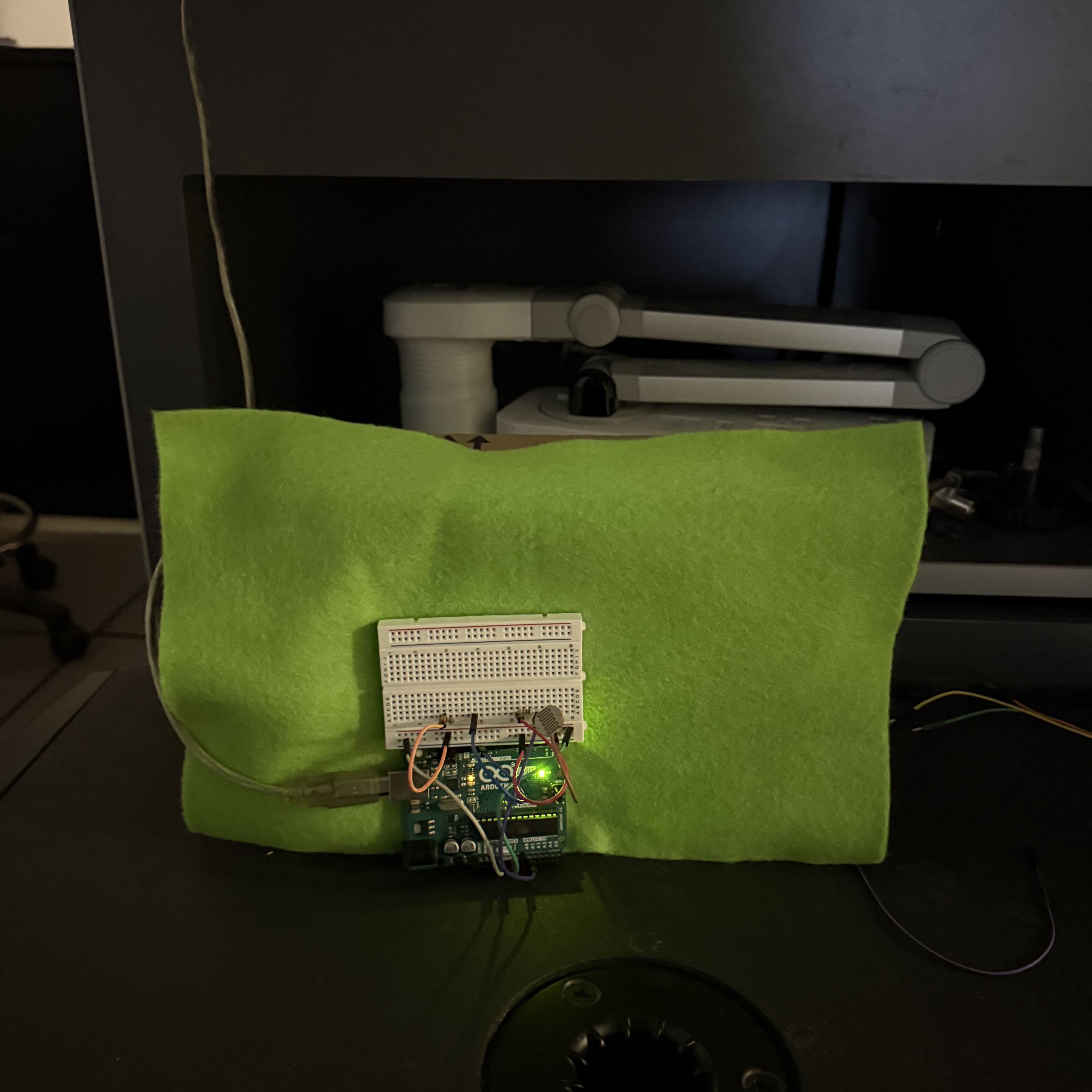 We made a prototype using a cardboard box covered with fabric, using the box to simulate a cushion and placing the Arduino in front of it to represent the final usage scenario. However, this prototype revealed several issues:

1. Comfort — If the sensor is placed on the surface of the cushion, the user will definitely feel uncomfortable when leaning on it.
2. Trigger accuracy — We need a way to ensure that TouchDesigner is activated only when the user leans on the cushion. If the room gets dark, the light sensor might also be triggered, which is clearly not what we want.
