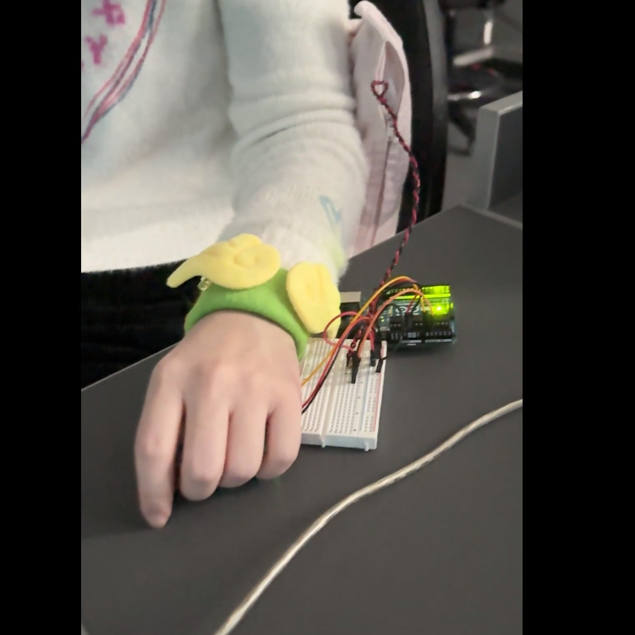 The prototype for Project 3 uses a force sensor and a pulse sensor connected to an Arduino to detect changes in pressure and the user's heart rate. When the user leans on or sits against the cushion, the sensorvalues change. These changes trigger TouchDesigner to display predefined visuals through a projector.
Depending on the user’s heart rate, the system presents either fast and intense geometric animations or calm and soothing geometric motions. It can serve as a reminder device or assist users in calming down, meditating, or falling asleep. The prototype consists of a cushion with a built-in force-sensor circuit and a wristband with an integrated pulse sensor, requiring only that the user lean on the cushion and wear the band to activate the system.<a href='https://youtube.com/shorts/zRFuHhrke08'>Prototype Demo Video</a>
